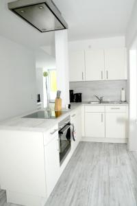 uma cozinha branca com armários brancos e um lavatório em Seeschwalbe em Scharbeutz
