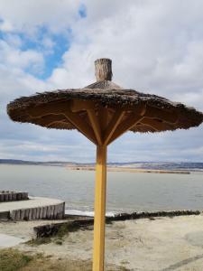 ein großer Sonnenschirm am Strand in der Nähe des Wassers in der Unterkunft Amur Vendégház in Gárdony