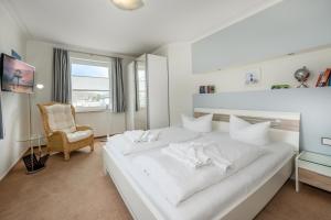 ヘリングスドルフにあるHaus Nordstern 2の白いベッドルーム(大きな白いベッド1台、椅子付)