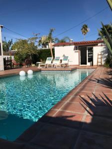 a swimming pool with chairs and a house at Casa De Vito in Palm Springs