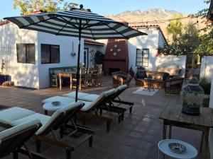 a patio with tables and chairs and an umbrella at Casa De Vito in Palm Springs