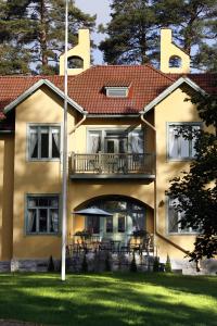 een groot geel huis met een balkon en een gazon bij Villa Urhola, Kruunupuisto in Punkaharju