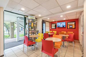 uma sala de jantar com mesas e cadeiras num restaurante em Premiere Classe Rouen Sud - Parc Des Expositions em Saint-Étienne-du-Rouvray