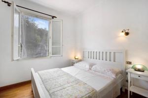 a white bedroom with a bed and a window at Mariuccia in Imperia