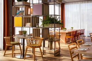 un restaurante con sillas de madera y mesas con plantas en IntercityHotel Karlsruhe en Karlsruhe