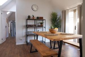 a dining room with a table and a clock on the wall at IndieHaus in Lincolnshire