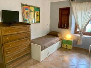 a bedroom with a bed and a dresser with a television at Home Langhe in Farigliano