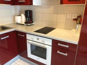 a kitchen with red cabinets and a white stove top oven at Charmant studio situé à proximité des thermes 30 in Amélie-les-Bains-Palalda
