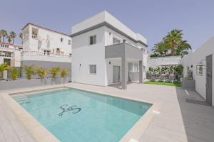 a white house with a swimming pool in front of it at Stunning Apartment - Near Los Cristianos in Chayofa