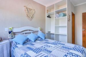 a bedroom with a blue and white bed with blue pillows at 2 Quartos com ar, piscina, sacada Gourmet a 1 km da praia Grande in Ubatuba