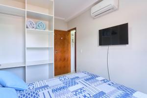 a bedroom with a bed and a flat screen tv at 2 Quartos com ar, piscina, sacada Gourmet a 1 km da praia Grande in Ubatuba +21 photos