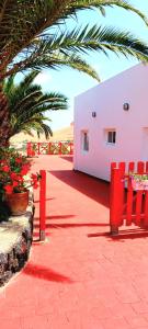 a patio with red chairs and a pink building at Casa Yahshua in Villaverde