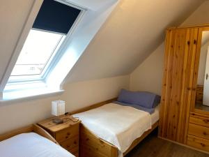 Un dormitorio abuhardillado con dos camas y una ventana. en Apartmenthaus am Watt Büsum, en Büsum