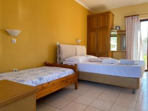 2 łóżka w pokoju z żółtymi ścianami w obiekcie Dimitra Rooms w mieście Leukada (miasto)