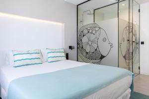 a white bedroom with a large bed and a glass wall at Sercotel Puerto de la Luz in Las Palmas de Gran Canaria