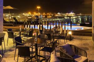 - une terrasse avec des tables et des chaises ainsi qu'une piscine la nuit dans l'établissement Sercotel Puerto de la Luz, à Las Palmas de Gran Canaria