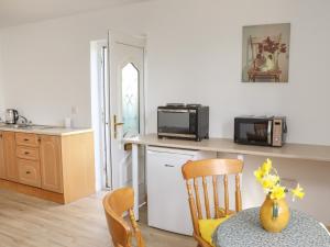 una cocina con una mesa con un jarrón de flores. en Wheatfield Lodge en Fethard on Sea
