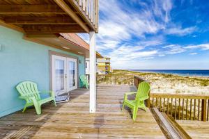 a porch with two green chairs and the ocean at Hakuna Matata in Gulf Shores
