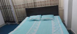 Una cama con dos almohadas azules encima. en Kompass Homestay - Affordable AC Room With Shared Bathroom in Naya Paltan Free WIFI, en Dhaka