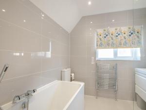a white bathroom with a tub and a window at Garway Cottage in Ross on Wye