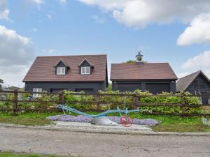 uma casa com uma cerca com um jardim de flores em frente em Leveret Lodge em Leavenheath