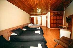 a bedroom with three beds in a room with wooden ceilings at Hotel Geneve in Campos do Jordão