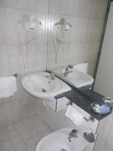 Baño blanco con 2 lavabos y espejo en Hotel Traghetto, en Civitavecchia