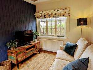 a living room with a couch and a tv and a window at The Pack Horse Exmoor National Park Allerford Riverside Cottage & Apartments in Minehead