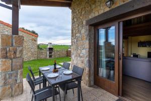 un patio con mesa, sillas y pared de piedra. en Villas Verdemar en Isla