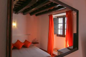 a mirror reflecting a bedroom with a bed and a window at Dom Nuno - Turismo de Habitacao in Monsaraz