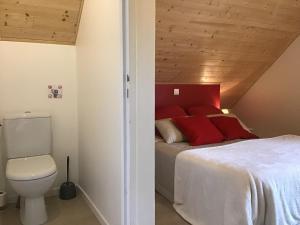 una camera da letto con letto con cuscini rossi e servizi igienici di Espace Acu-Nature a Saint-Évarzec