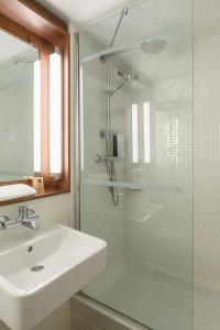 a white bathroom with a sink and a shower at Campanile Lyon Bron Eurexpo in Bron