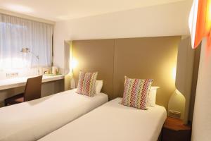um quarto de hotel com duas camas e uma secretária em Campanile Lyon Bron Eurexpo em Bron