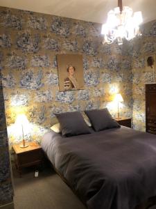 1 dormitorio con 1 cama con papel pintado de flores azul en Abbaye de Saint Jean de Bonneval en Saint-Jean-de-Thouars