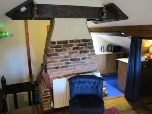 a living room with a brick fireplace and a blue chair at Bridge Stores in Fritton Norfolk