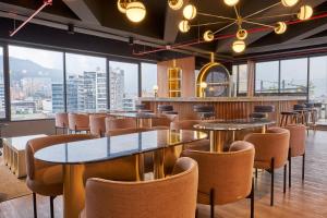 een restaurant met tafels en stoelen en grote ramen bij ICON 100 Luxury Apartasuites in Bogota