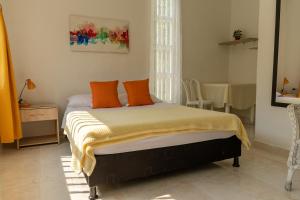 a bedroom with a bed with orange pillows on it at Casa El Limonar Garzón Hospedaje Campestre in Garzón