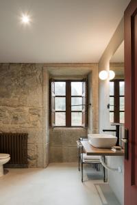 a bathroom with a sink and a toilet and a window at Pazo da Buzaca in Moraña