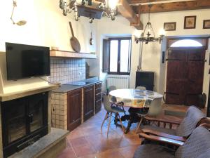ein Wohnzimmer mit einem Tisch und eine Küche mit einem TV in der Unterkunft Maison Fonticella, HOST APARTMENTS in Rivisondoli