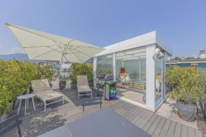 een patio met een parasol, stoelen en een grill bij La Terrazza sul Lago in Verbania