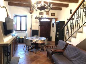 ein Wohnzimmer mit einem Tisch, Stühlen und einer Treppe in der Unterkunft Maison Fonticella, HOST APARTMENTS in Rivisondoli