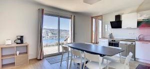 eine Küche mit einem Tisch und Stühlen sowie einem großen Fenster in der Unterkunft Gîte Le Panoramique in Bilieu