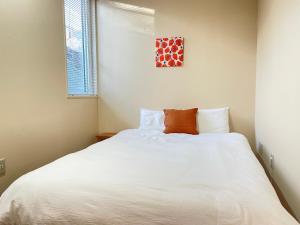 a bedroom with a white bed with a pillow on it at Minowa airbnb in Yubari