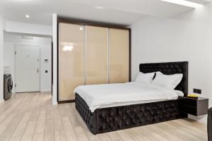 una camera con un grande letto con testiera nera di The Central Deluxe a Bucarest