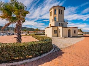 uma torre do relógio com uma palmeira ao lado de um passeio em Sardinia Family Villas - Cannigione Beach Apartments em Cannigione