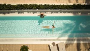 two people are swimming in a swimming pool at Secrets Lanzarote Resort & Spa - Adults Only (+18) in Puerto Calero
