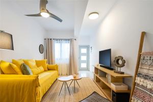 a living room with a yellow couch and a tv at Aretousa InCreteble Cretan Residences Collection in Sitia