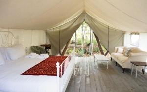 a bedroom with a tent with a bed and a couch at Fronterra Wellness Farm & Camp in Hillier