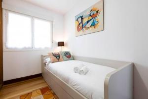 a white room with a bed with a painting on the wall at Zurubi-gain. Basquenjoy in Hondarribia