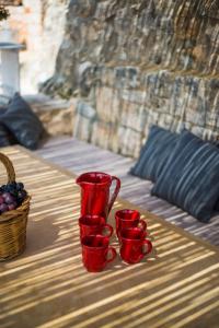 three red cups on a table with a basket of grapes at Trullo fiore in Ostuni